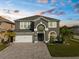 Elegant two-story home with a manicured lawn, a paver driveway, and a two-car garage at 3654 Beneraid St, Land O Lakes, FL 34638