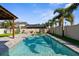 The refreshing swimming pool is surrounded by outdoor kitchen, mature palms, and artificial turf at 3654 Beneraid St, Land O Lakes, FL 34638