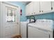 Bright laundry room with washer, dryer, storage cabinets, and a decorative exterior door at 36745 Kimela Ave, Zephyrhills, FL 33542
