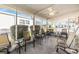 Screened-in patio area with tiled flooring, ceiling fan, and multiple outdoor furniture seating arrangements at 36745 Kimela Ave, Zephyrhills, FL 33542