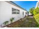 Side exterior of home shows neutral toned paint, green grass, small plants and hose neatly put away at 479 80Th Way, St Pete Beach, FL 33706