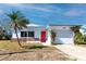 Charming home with a vibrant red door, a lush vine-covered garage, and a palm tree at 479 80Th Way, St Pete Beach, FL 33706