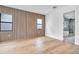 Bright bedroom featuring wood accent wall, hardwood floors, and sleek, modern black-framed windows at 5017 W Dickens Ave, Tampa, FL 33629