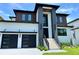Contemporary home features a black two-car garage, and landscaped yard with modern staircase leading to the front door at 5017 W Dickens Ave, Tampa, FL 33629