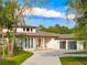 Elegant single-story home showcasing clean white facade, tile roof, three-car garage, and lush landscaping at 5546 Drexel Rd, Land O Lakes, FL 34638