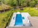 Aerial view of a backyard featuring a modern pool, patio, mature landscaping, and play area at 5546 Drexel Rd, Land O Lakes, FL 34638
