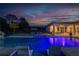 Nighttime view of swimming pool with tropical landscaping and an outdoor kitchen at 5546 Drexel Rd, Land O Lakes, FL 34638