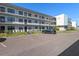 View of the building's facade, manicured lawn, parking spaces, and guest parking at 5969 Terrace Park N Dr # 203, St Petersburg, FL 33709