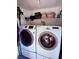 Bright laundry room featuring front loading Samsung washer and dryer and storage shelf at 7138 E Bank Dr # 7138, Tampa, FL 33617
