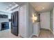 Hallway view of the entry door and kitchen, with a modern black stainless steel refrigerator at 74 Gulf Blvd # 3B, Indian Rocks Beach, FL 33785