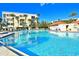 A large sunny pool with clear blue water in a tropical setting and building views at 7564 Bayshore Dr # 207, Treasure Island, FL 33706