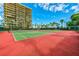 Well-maintained outdoor tennis courts with palm trees, a tall building, and clear skies at 7564 Bayshore Dr # 207, Treasure Island, FL 33706