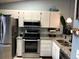 Well-equipped kitchen with stainless steel appliances, granite counters, and white cabinetry at 1020 Bowsprit Ln # X, Holiday, FL 34691