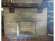 Close-up of a stone fireplace with a wood mantel and brick firebox at 1044 Virginia Dr, Sarasota, FL 34234