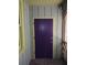 Front door with a unique violet color flanked by green wood paneling and a covered porch at 1044 Virginia Dr, Sarasota, FL 34234