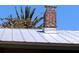Durable metal roof with a well-maintained brick chimney, under a blue sky with palm trees at 1044 Virginia Dr, Sarasota, FL 34234