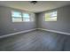 Bright bedroom with light gray walls, two windows, and light gray wood-look floors at 2016 Essex Dr, Holiday, FL 34691