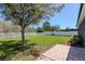Green backyard featuring an large tree and white vinyl fence, a brick walkway along the side of the house at 2208 Landside Dr, Valrico, FL 33594