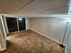 A carpeted basement featuring sliding glass doors, a small window, and painted walls in a neutral tone at 2484 Roberta St, Largo, FL 33771
