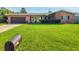 Charming one-story brick home featuring a lush front lawn, manicured bushes, and an attached garage at 2484 Roberta St, Largo, FL 33771