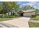 Charming single-story home with well-manicured lawn, large trees and a lengthy driveway leading to an attached garage at 3462 Sutton Pl, Palm Harbor, FL 34684
