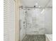 This is a close-up of a glass-enclosed shower with marble tiles and a gray stone floor at 3462 Sutton Pl, Palm Harbor, FL 34684