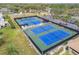 Wide aerial shot of the blue and green tennis courts, showcasing the ample parking in the background at 3462 Sutton Pl, Palm Harbor, FL 34684