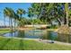 Scenic view of the Highland Lakes entrance featuring a pond, fountain, and lush greenery at 3462 Sutton Pl, Palm Harbor, FL 34684
