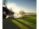 Sunrise view over the golf course green with a red flag, a placid lake, and trees emerging from the morning fog at 36750 Us Highway 19 N # 19308, Palm Harbor, FL 34684