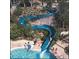 A large, winding water slide going into a pool area with lush greenery, a lifeguard, and people enjoying the water at 36750 Us Highway 19 N # 19308, Palm Harbor, FL 34684