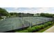 This image showcases multiple well-maintained tennis courts with green surfaces, nets, and shaded seating areas surrounded by lush greenery at 36750 Us Highway 19 N # 19308, Palm Harbor, FL 34684