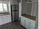 An open kitchen has stainless steel refrigerator, granite counters, white cabinets and modern flooring at 10530 77Th Ter # 224, Seminole, FL 33772