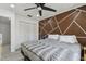 A bedroom boasting a geometric accent wall, plush bed, and a closet with white louvered doors at 12738 Wood Trail Blvd, Tampa, FL 33625