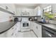 Galley kitchen featuring white appliances, white cabinets, dark countertops and tile flooring at 12738 Wood Trail Blvd, Tampa, FL 33625