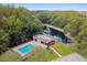 Aerial view of a community pool surrounded by a fence, trees, and a lakeside at 12738 Wood Trail Blvd, Tampa, FL 33625