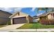 Side view of the property showcasing a well-manicured lawn and a two-car garage at 13052 Ogden Glade Rd, Dade City, FL 33525