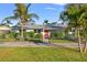 Charming single-story home with lush landscaping, vibrant plants and a welcoming orange front door at 1500 Carson Ne Cir, St Petersburg, FL 33703