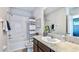 Full bath with tub, white tiled walls, dark vanity and framed mirror at 17257 Bigleaf Mahogany Ln, Land O Lakes, FL 34638