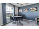 A home office with blue accent walls, natural light, and views overlooking the community at 17289 Bigleaf Mahogany Ln, Land O Lakes, FL 34638