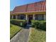 Charming single-story home featuring a red tile roof, a well-maintained lawn, and lush green bushes at 19029 Us Highway 19 N # 12E, Clearwater, FL 33764
