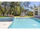 Gorgeous pool features spa and fountains amidst a lush backyard setting with an outdoor dining area at 2216 Clement Rd, Lutz, FL 33549