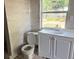 Bathroom featuring white cabinet, window, toilet, and tiled wall at 2410 Harper St, Tampa, FL 33605