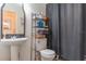 Compact bathroom featuring a pedestal sink, toilet, shelving, and a shower with a gray patterned curtain at 313 Jefferson S Ave, Oldsmar, FL 34677