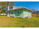 Charming light green home with a manicured lawn and mature landscaping under a clear blue sky at 313 Jefferson S Ave, Oldsmar, FL 34677