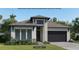 Inviting one-story home featuring a stone facade, black garage door, and beautifully manicured lawn at 322 Holly Bank Ave, Nokomis, FL 34275