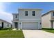 Two-story home with a gray exterior, two-car garage, landscaped front yard, and sidewalk to the front door at 34110 Jasper Stone Dr, Wesley Chapel, FL 33543