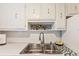 A clean kitchen is displayed with a stainless steel sink, tiled backsplash, and laminate countertops at 5267 81St N St # 18, St Petersburg, FL 33709