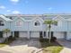 Exterior view of a modern townhome featuring a garage, lush landscaping, and a well-maintained facade at 649 Garland Cir, Indian Rocks Beach, FL 33785