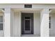 Covered front porch entrance with pillars, house number and screen door at 7811 Roma Dune Dr, Wesley Chapel, FL 33545