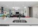 Bright, open-concept kitchen with a double sink, island and a view to the living area with modern lighting fixtures at 7811 Roma Dune Dr, Wesley Chapel, FL 33545